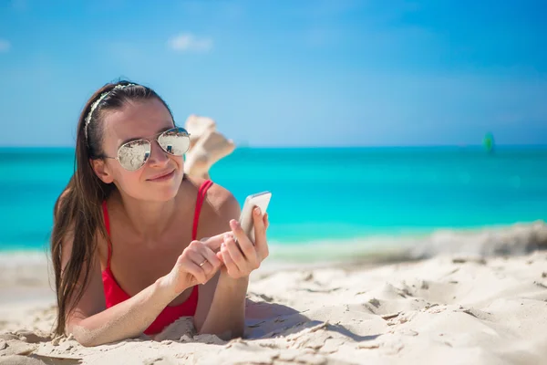 Ung kvinna med sin mobiltelefon på exotiska strand — Stockfoto