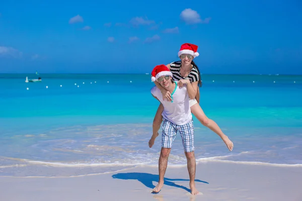 Kırmızı santa şapkalar onların tatil tropikal sırasında genç mutlu çift — Stok fotoğraf