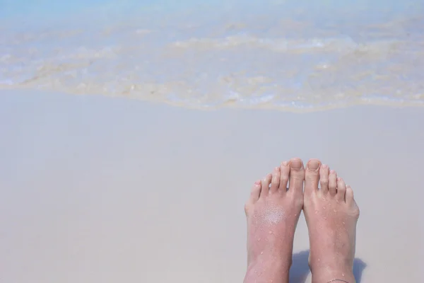 Κοντινό πλάνο των γυναικείων ποδιών σε λευκή αμμώδη παραλία — Φωτογραφία Αρχείου