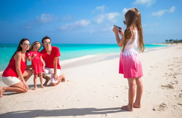 Mała dziewczynka robi zdjęcie przez telefon swojej rodziny na plaży. — Zdjęcie stockowe