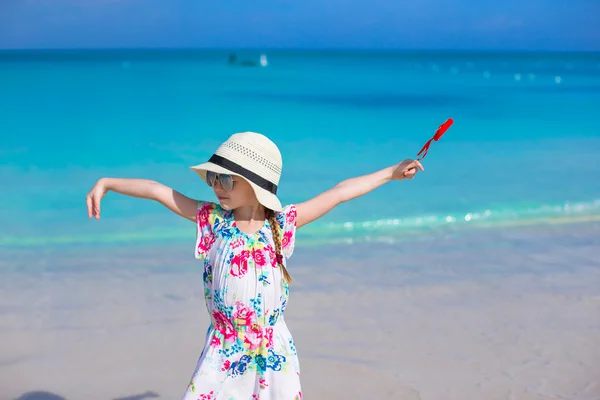 Kleines glückliches Mädchen mit rotem Herz in den Händen an einem tropischen Strand — Stockfoto