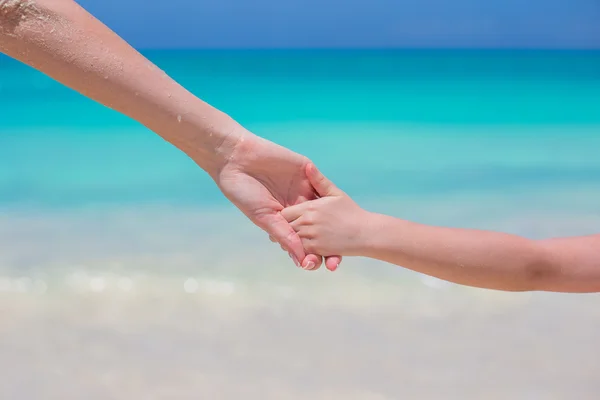 Close up of father and little daughter holding each other hands at beach — Stock Photo, Image