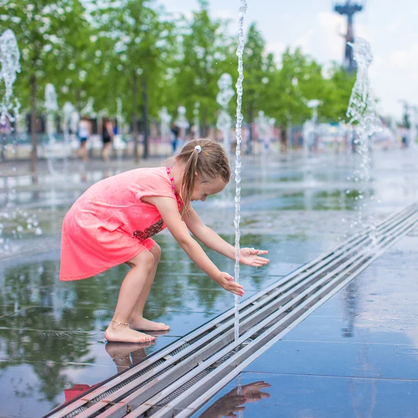 Klein meisje plezier hebben in open straat fontein op warme zomerdag — Stockfoto