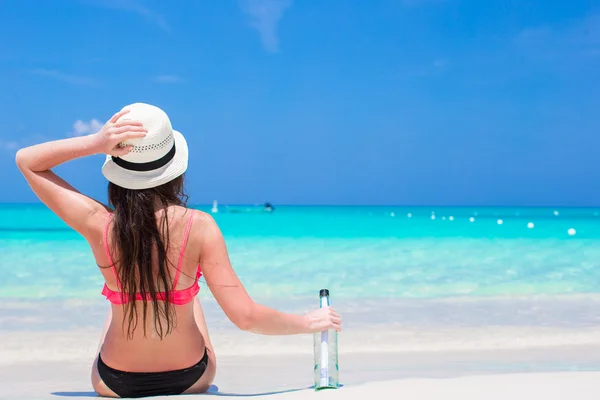 Bella giovane donna con bottiglia seduta sulla spiaggia — Foto Stock