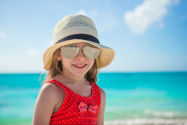 Happy little girl in hat on beach during summer vacation