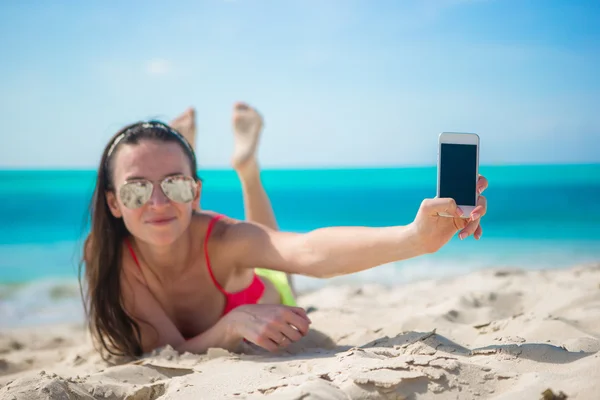 Młoda kobieta z jej telefon komórkowy na plaży biały — Zdjęcie stockowe