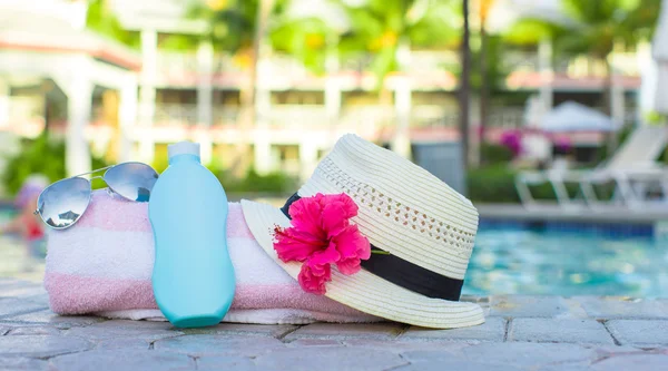Crema solar, sombrero, gafas de sol, flores y torre cerca de la piscina — Foto de Stock