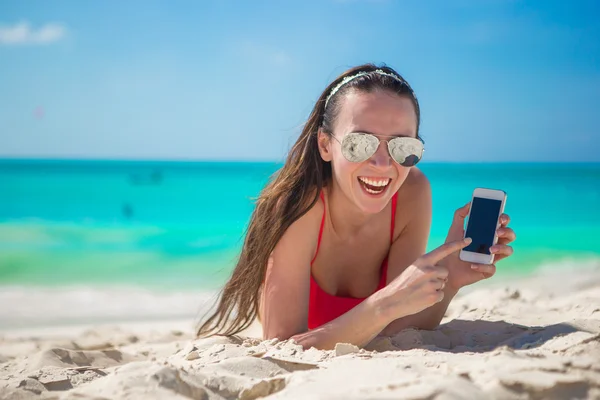 Ung kvinna liggande på vit sand och prata av mobiltelefon — Stockfoto
