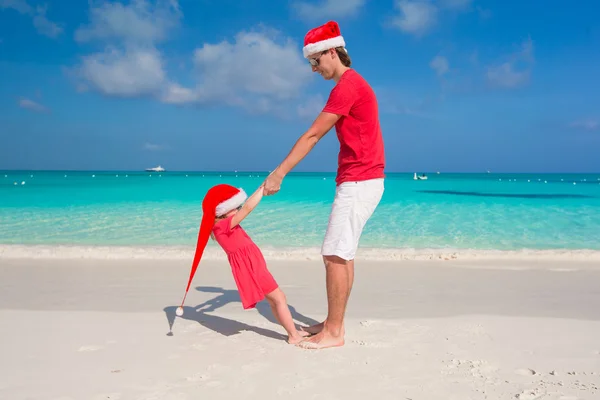 小女孩，在圣诞老人的帽子的快乐老爸在地处热带的海滩玩得开心 — 图库照片
