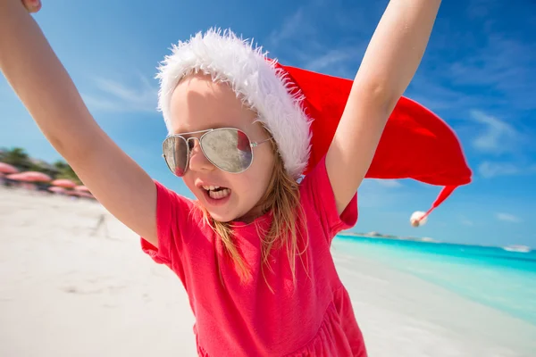 Schattig meisje in rode kerstmuts veel plezier op het strand — Stockfoto