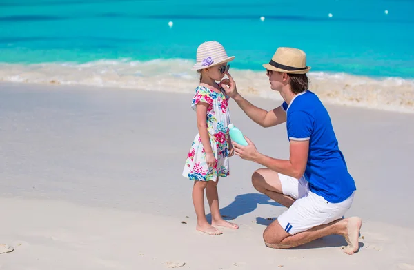 Vater cremt seine kleine Tochter mit Sonnencreme ein — Stockfoto
