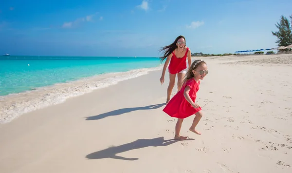 年轻的妈妈和小女孩奔跑在地处热带的海滩 — 图库照片