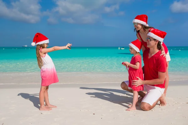 在圣诞老人的帽子在地处热带的海滩上尽情的家庭 — 图库照片