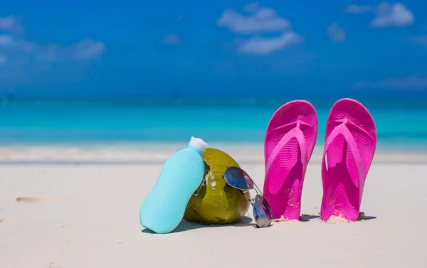 Flip flops, καρύδα και suncream σχετικά με λευκή άμμο — Φωτογραφία Αρχείου