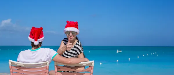 Familie av to i nissehatter som sitter på strandstol – stockfoto