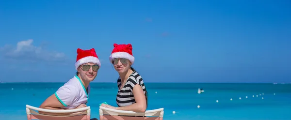 Jong koppel in santa hoeden tijdens strandvakantie — Stockfoto