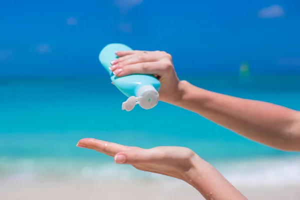 Mãos de mulher pondo protetor solar de uma garrafa de creme solar — Fotografia de Stock