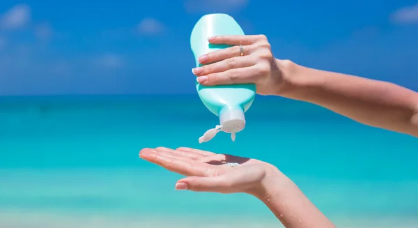 Woman hands putting sunscreen from suncream bottle — Stock Photo, Image