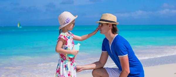 Little girl rubs sunscreen on nose of her dad — Stock Photo, Image