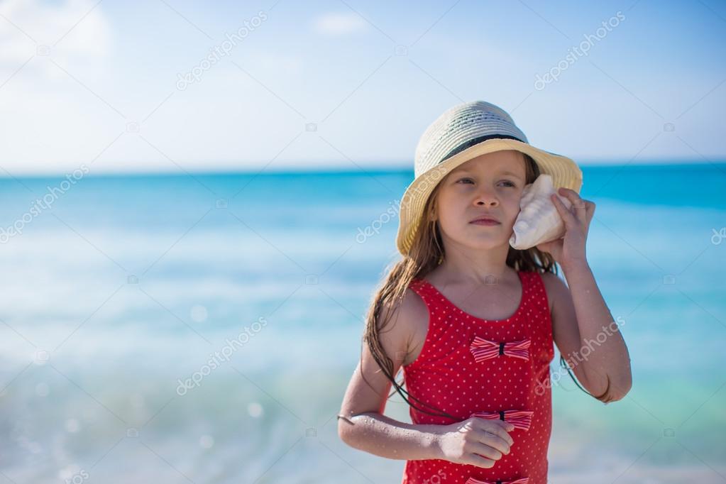 Little cute girl with seashell in hands at tropical beach