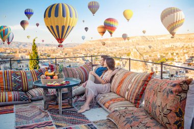 Kapadokya, Türkiye 'de sıcak hava balonları seyreden mutlu genç çift.
