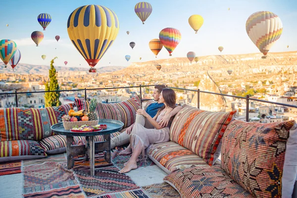 Gelukkig jong stel tijdens zonsopgang kijken naar hete lucht ballonnen in Cappadocia, Turkije Stockfoto