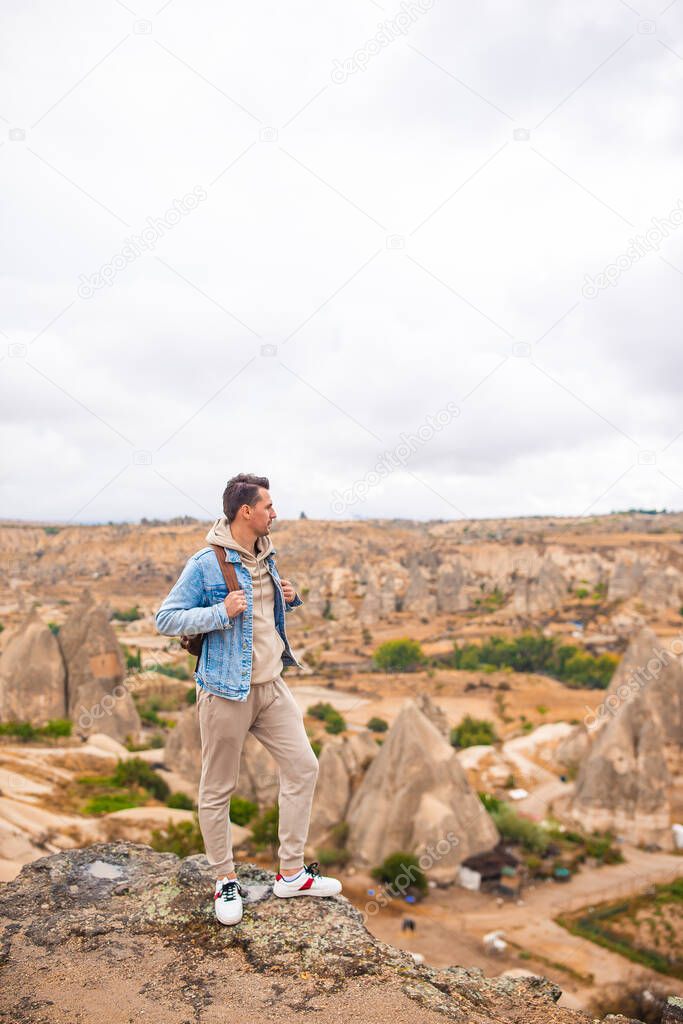 Happy man outdoor on edge of cliff enjoy the view on mountain top rock