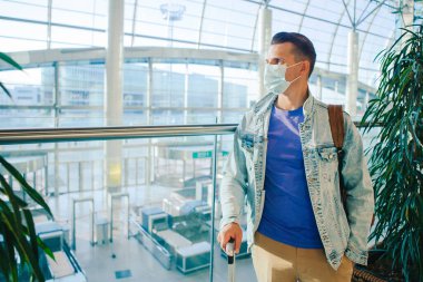 Uluslararası havaalanı salonunda virüsü önlemek için maske takan adam uçuş uçağını bekliyor.. 