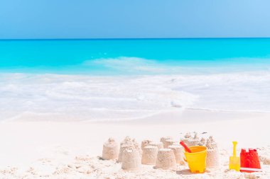 Plastik çocuk oyuncaklarıyla beyaz tropik plajda kumdan kale