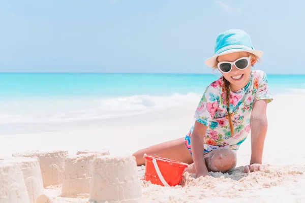 Malá dívka na tropické bílé pláži tvorby písku hrad — Stock fotografie
