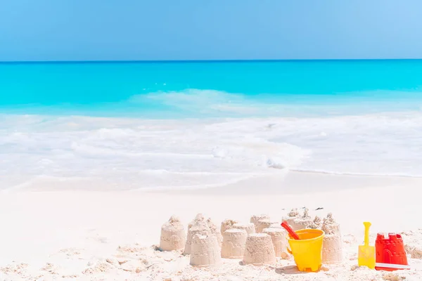 Castillo de arena en la playa tropical blanca con juguetes de plástico para niños — Foto de Stock