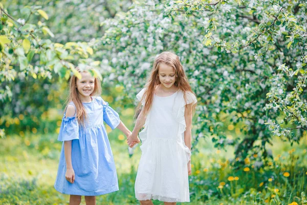 Adorables niñas en el jardín de manzanos en flor en el día de primavera —  Fotos de Stock