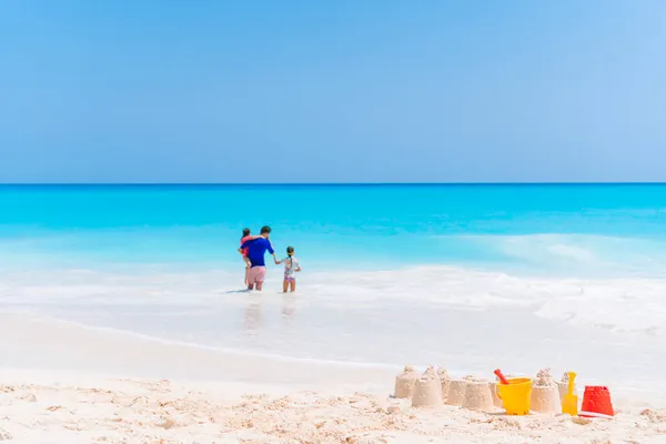 Glücklicher Vater und seine entzückenden kleinen Töchter am tropischen Strand lizenzfreie Stockfotos