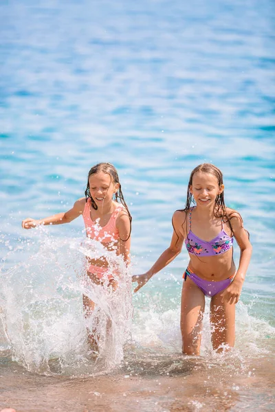 Ευτυχισμένα παιδιά πιτσιλίζουν στα κύματα κατά τη διάρκεια των καλοκαιρινών διακοπών στην τροπική παραλία. Τα κορίτσια παίζουν στη θάλασσα. — Φωτογραφία Αρχείου