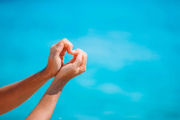 ターコイズブルーの海に対して心の形で女性の手 — ストック写真