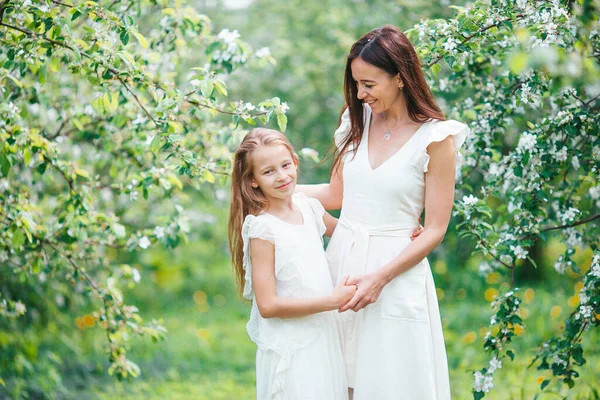 Urocza dziewczynka z młodą matką w kwitnącym wiśniowym ogrodzie w piękny wiosenny dzień — Zdjęcie stockowe