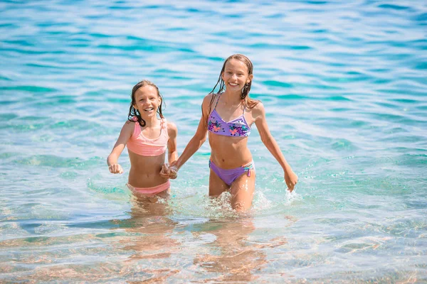 Bambini felici che schizzano sulle onde durante le vacanze estive sulla spiaggia tropicale. Le ragazze giocano al mare. — Foto Stock