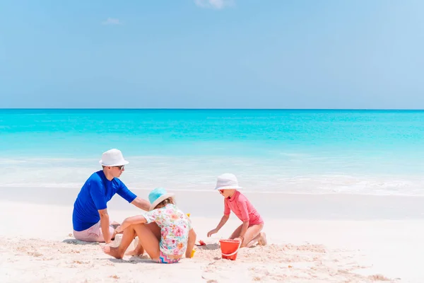 Otec a děti staví hrad z písku na tropické pláži. Rodinné hraní s hračkami na pláži — Stock fotografie