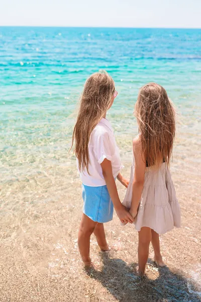Mutlu çocuklar yaz tatilinde tropikal plajda dalgalara su sıçratıyorlar. Kızlar denizde oynar. — Stok fotoğraf