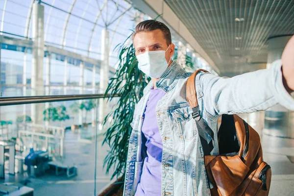 Mężczyzna noszący maskę zapobiegającą wirusowi w salonie międzynarodowego lotniska czekając na samolot. — Zdjęcie stockowe