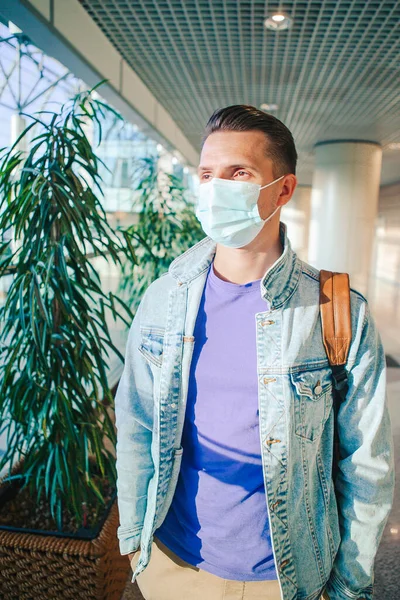 Mężczyzna noszący maskę zapobiegającą wirusowi w salonie międzynarodowego lotniska czekając na samolot. — Zdjęcie stockowe