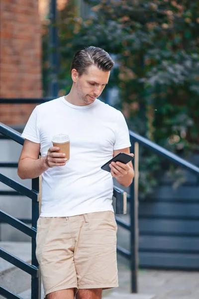 Ung man dricker kaffe i stan utomhus — Stockfoto