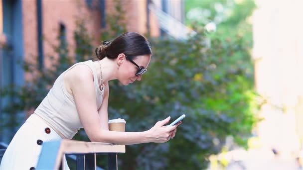 Lycklig kvinna med smartphone på europeisk gata. Ung attraktiv turist utomhus i staden — Stockvideo