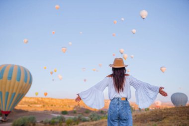 Güneş doğarken Kapadokya, Türkiye 'de sıcak hava balonları seyreden mutlu kadın