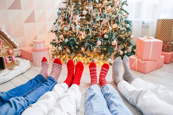 Κοντινές φωτογραφίες οικογενειακών ποδιών με μάλλινες κάλτσες δίπλα στο χριστουγεννιάτικο δέντρο — Φωτογραφία Αρχείου