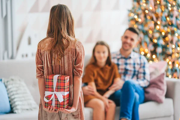 Arkaya bakan çocuk Noel ağacının yanında bir hediye kutusu tutuyor..