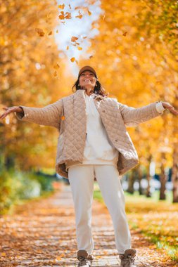 Sonbahar konsepti: Sonbahar parkında sonbahar yaprakları altında kahve içen güzel bir kadın.