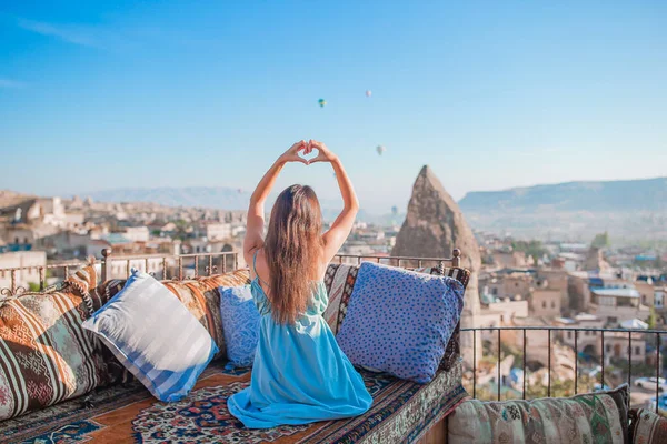 Gelukkige jonge vrouw tijdens zonsopgang kijken naar hete lucht ballonnen in Cappadocia, Turkije — Stockfoto
