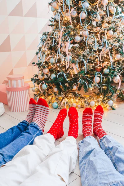 Κοντινές φωτογραφίες οικογενειακών ποδιών με μάλλινες κάλτσες δίπλα στο χριστουγεννιάτικο δέντρο — Φωτογραφία Αρχείου