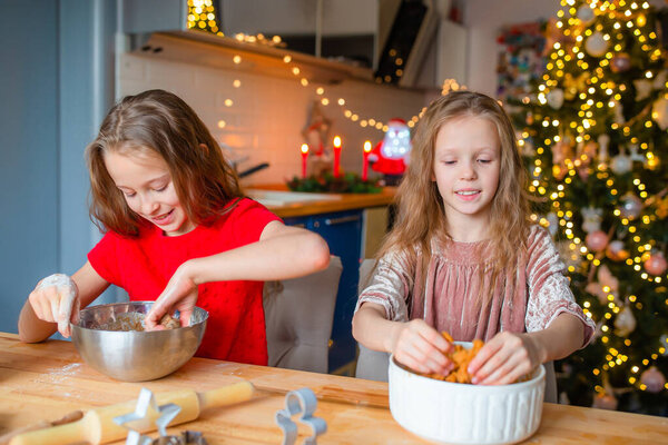 Little girls together cooking Christmas cookies at home in the kitchen